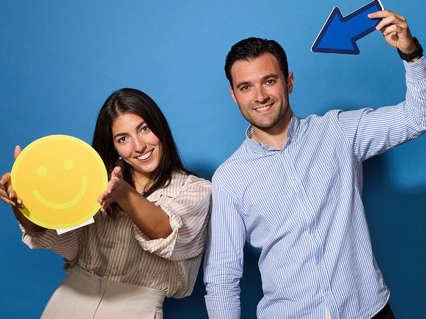 Γυναίκα και άντρας κρατούν καρτέλες με χαρούμενο πρόσωπο και βέλος.